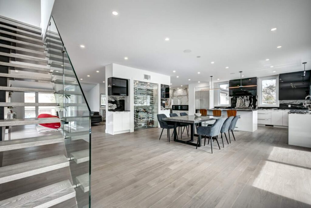 Spacious living room with modern furnishings, large windows, and views of a landscaped backyard with a pool.