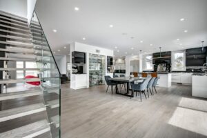 Spacious living room with modern furnishings, large windows, and views of a landscaped backyard with a pool.